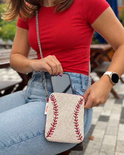 White and red baseball stitch beaded cell phone crossbody shown holding a phone