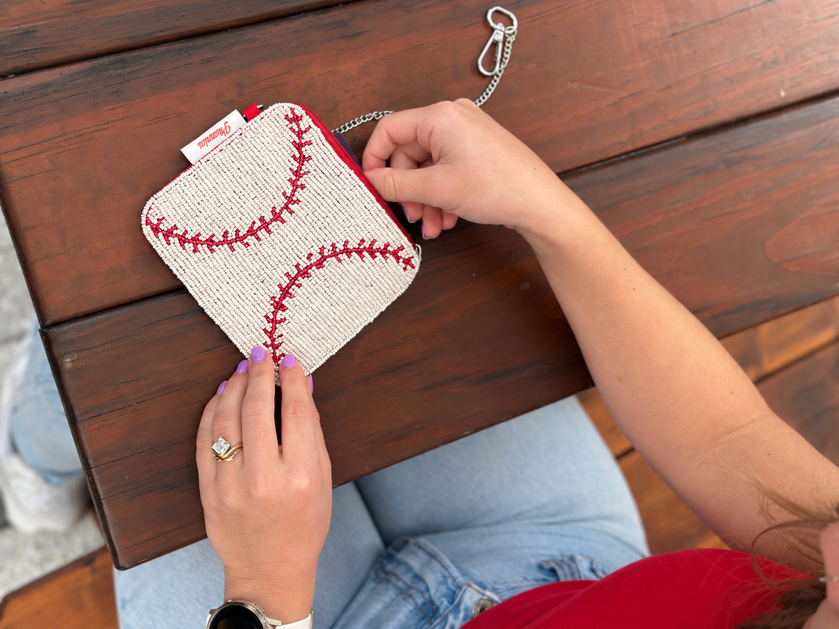 White and red baseball stitch beaded coin purse shown on wooden table