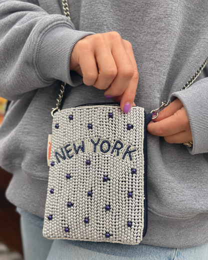 Close-up of NEW YORK white and navy dot beaded cell phone crossbody styled with gray sweatshirt