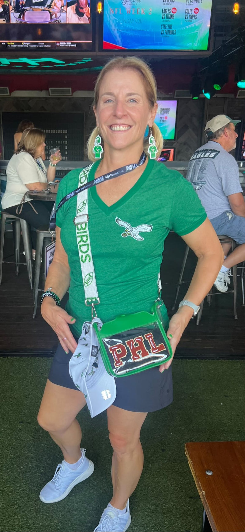 Eagles fan wearing a green BIRDS beaded purse strap and clear PHILA stadium bag at a sports bar