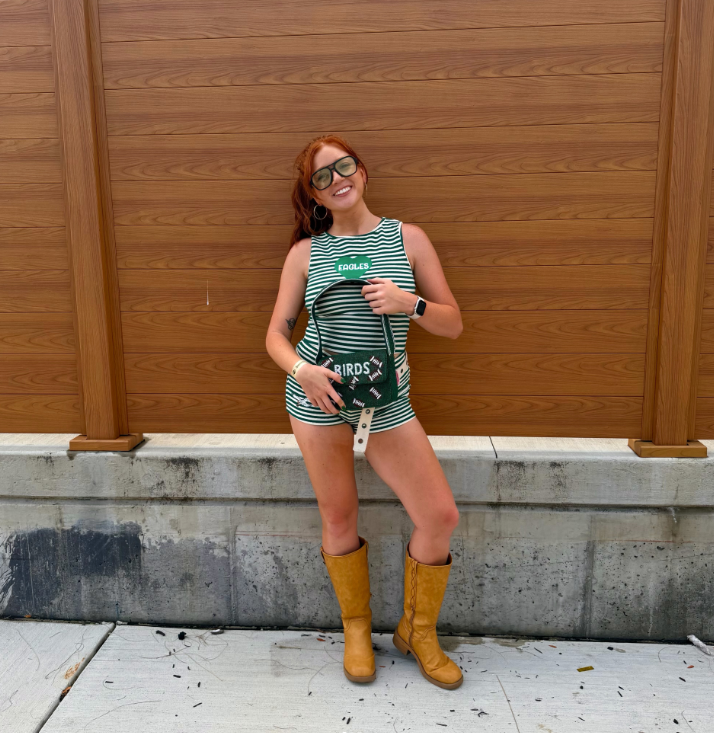 Woman in green striped Eagles outfit wearing a BIRDS beaded shoulder bag and tan boots