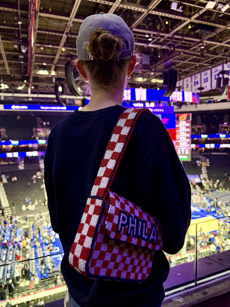 Fan wearing red and white checkerboard PHILA beaded bag at basketball game