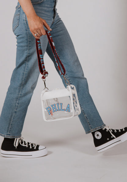 White PHILA clear crossbody bag with burgundy and powder blue RING THE BELL strap